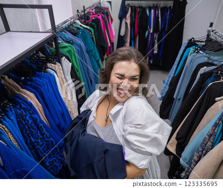 Top view of a chubby-cheeked woman holding an armful of clothes in a plus size store. Top view of a chubby-cheeked woman holding an armful of clothes in a plus size store. 123335695