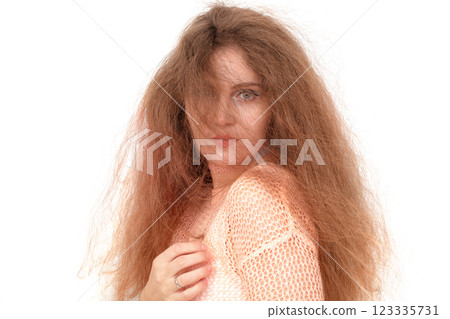 A woman with long brown hair is wearing a white shirt and holding her hand to her face. 123335731