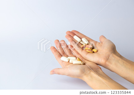 on white background, on the outstretched palms of female hands, there are pills and vitamins of different shapes and colors. suicidal thoughts, depression, health care. 123335844