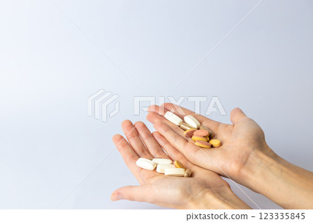 on white background, on the outstretched palms of female hands, there are pills and vitamins of different shapes and colors. suicidal thoughts, depression, health care. 123335845