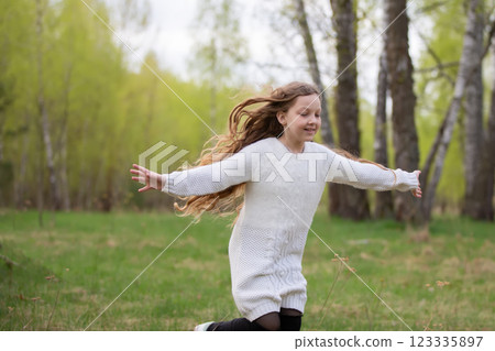 A little girl runs through the spring forest. A child on a walk in the park. A little girl runs through the spring forest. A child on a walk in the park. 123335897