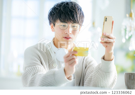 Young man looking at smartphone and credit card 123336062