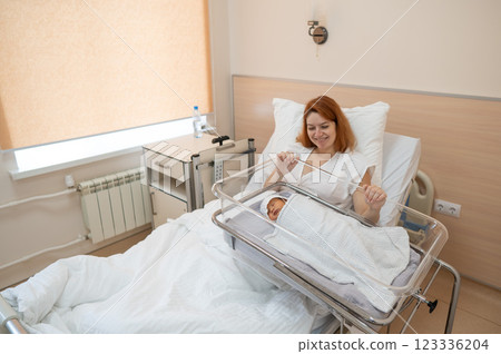 A young mother admires her newborn son in the maternity hospital.  123336204