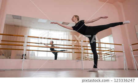 Caucasian blonde woman is practicing ballet in class. Ballerina rehearsing at the barre. Caucasian blonde woman is practicing ballet in class. Ballerina rehearsing at the barre. 123336247