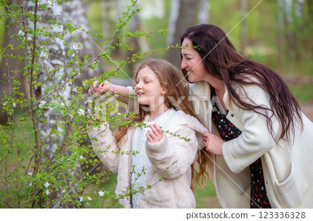 Mom and daughter take a walk in a blooming spring park looking at the trees. Mom and daughter take a walk in a blooming spring park looking at the trees. 123336328