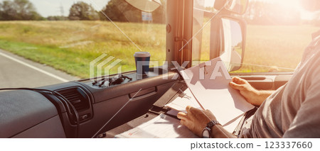 Truck driver sitting in the car and writing documents. 123337660