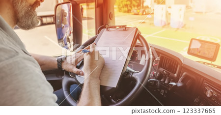 Truck driver sitting in the car and writing documents. 123337665