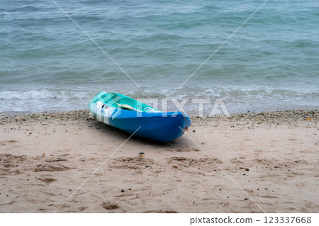 A blue and green kayak on a tropical sandy beach with the emerald green sea in the background 123337668