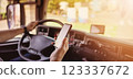 Truck driver sitting behind the wheel and looking at the smartphone. 123337672