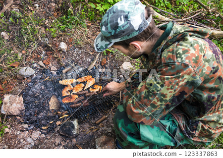 Soldier grilling meat on a makeshift barbecue in the forest 123337863