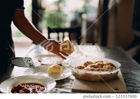 Housewife puts pampushka on a plate next to a plate of borscht Housewife puts pampushka on a plate next to a plate of borscht 123337900