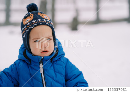 Little sad girl with tearful eyes stands on the snow in the forest 123337981