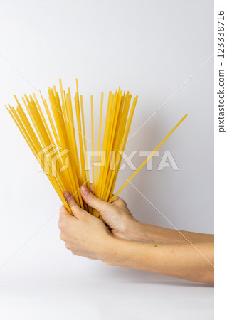 on a white background, young female thin hands hold durum spaghetti spread out like fan in their hands Italian cuisine traditional food bright yellow color spaghetti on a white background, young female thin hands hold durum spaghetti spread out like fan in their hands Italian cuisine traditional food bright yellow color spaghetti 123338716