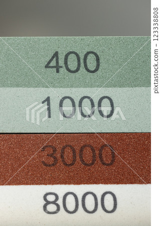 closeup dark background on table lies red and green equipment a set for sharpening and polishing kitchen knives and various blades different abrasiveness of stones a retainer for knives numbers 123338808