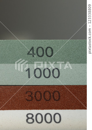 closeup dark background on table lies red and green equipment a set for sharpening and polishing kitchen knives and various blades different abrasiveness of stones a retainer for knives closeup dark background on table lies red and green equipment a set for sharpening and polishing kitchen knives and various blades different abrasiveness of stones a retainer for knives 123338809
