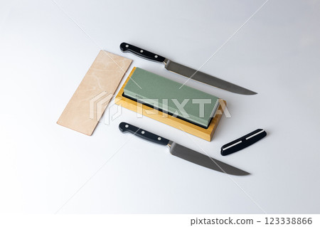white background on stand lies all the equipment a set for sharpening and polishing kitchen knives and various blades different abrasiveness of stones a retainer for knives sheet tanned leather 123338866
