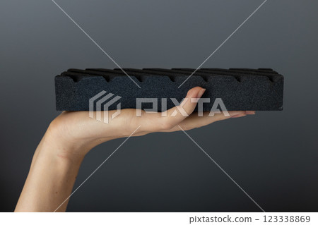 closeup on a dark gray background on a woman s palm lies a large abrasive grooved stone on top for sharpening knives and blades, an old method 123338869