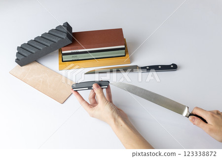 white background on counter lies all the equipment - a set for sharpening and polishing kitchen knives - the girl's hands are fixing the fuse and the locking device for knife protection against cuts white background on counter lies all the equipment - a set for sharpening and polishing kitchen knives - the girl's hands are fixing the fuse and the locking device for knife protection against cuts 123338872