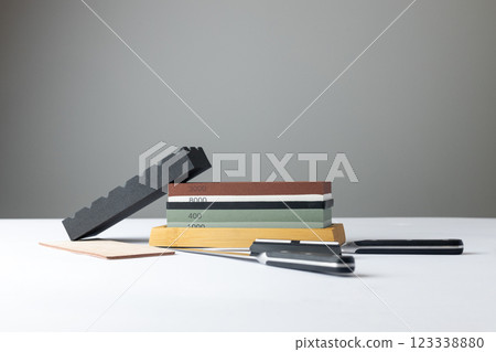 white background on stand lies all the equipment a set for sharpening and polishing kitchen knives and various blades different abrasiveness of stones a retainer for knives sheet tanned leather knives white background on stand lies all the equipment a set for sharpening and polishing kitchen knives and various blades different abrasiveness of stones a retainer for knives sheet tanned leather knives 123338880