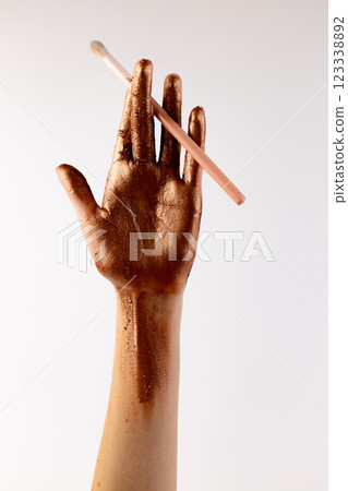 Aesthetic Bronze Hand with Makeup Brush: Captivating Elegance and Artistry on Display for Beauty and Cosmetic Inspiration 123338892