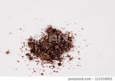 A Close-Up Image of Brown Granular Substance Deposited on a Light Background, Highlighting Textures and Various Particle Sizes in an Artistic Arrangement A Close-Up Image of Brown Granular Substance Deposited on a Light Background, Highlighting Textures and Various Particle Sizes in an Artistic Arrangement 123338903
