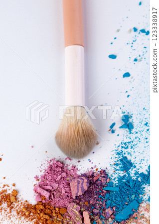 Colorful Makeup Brush with Vibrant Powder Pigments Spread Across a White Background: A Creative Artistic Display of Beauty Products for Makeup Enthusiasts 123338917