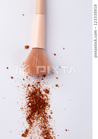 Close-Up of a Makeup Brush with Bronzing Powder Spilled on a Clean White Surface for Perfect Beauty Applications and Stylish Aesthetics, Ideal for Beauty Photography 123338919