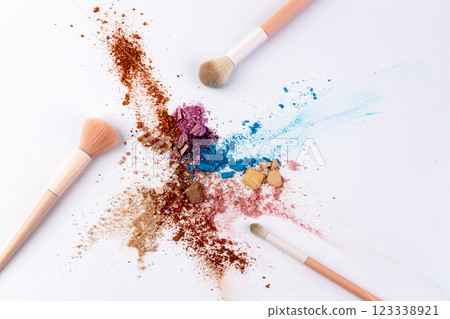 Vibrant Spectrum of Makeup Pigments and Brushes Artfully Dispersed on a White Surface, Showcasing Beauty Tools and Colorful Cosmetic Powders 123338921