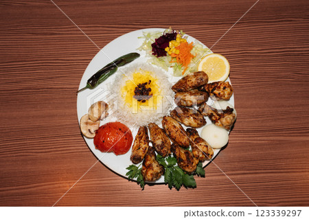 Turkish chicken kebab plate with rice and salad on wooden background. Retro flash food photography Turkish chicken kebab plate with rice and salad on wooden background. Retro flash food photography 123339297