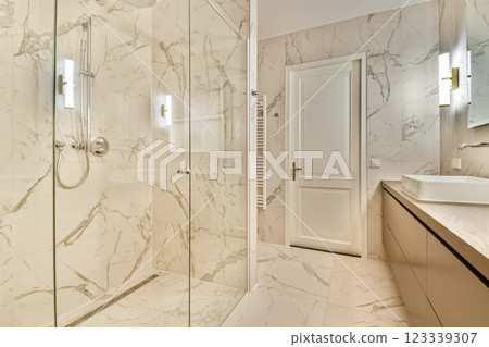 A stunning interior of a modern bathroom featuring elegant marble textures, sleek fixtures, and a spacious shower design. Bright and inviting ambiance. 123339307