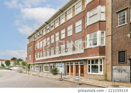 A stylish modern brick building featuring large windows, located on a quiet street with greenery. The architecture reflects contemporary design trends in urban settings. A stylish modern brick building featuring large windows, located on a quiet street with greenery. The architecture reflects contemporary design trends in urban settings. 123339314