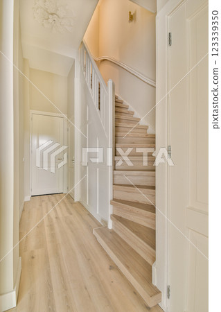 A well-lit modern interior featuring a staircase with light wood flooring and neutral walls, showcasing a contemporary design aesthetic. A well-lit modern interior featuring a staircase with light wood flooring and neutral walls, showcasing a contemporary design aesthetic. 123339350