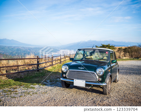 A green classic car (Mini Rover) parked at a lookout point with a beautiful view A green classic car (Mini Rover) parked at a lookout point with a beautiful view 123339704