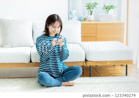 A young woman operating a smartphone in a room 123340274