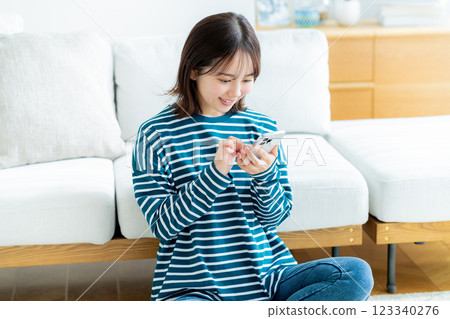 在房間裡操作智慧型手機的年輕女子 123340276
