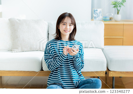 A young woman operating a smartphone in a room 123340277