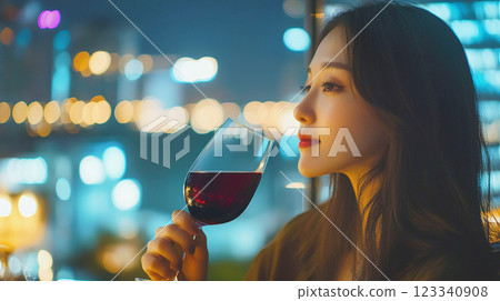 A woman looking at the night view with a glass of wine 123340908