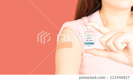 International HPV awareness day concept. Woman holding HPV vaccine vial while showing vaccinated arm with medical adhesive bandage strip after vaccine injection over pink background. 123340927