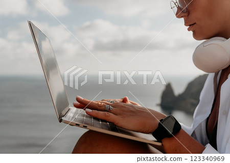 Laptop, Woman, Ocean - A woman works on her laptop while overlooking the ocean on a cliffside. 123340969