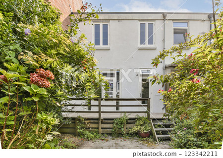 A picturesque house with blooming flowers and greenery, showcasing a welcoming porch and serene outdoor atmosphere. Perfect for nature lovers. A picturesque house with blooming flowers and greenery, showcasing a welcoming porch and serene outdoor atmosphere. Perfect for nature lovers. 123342211