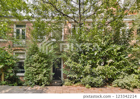 This image showcases a charming brick house enveloped in vibrant greenery, exemplifying a harmonious blend of architecture and nature. 123342214