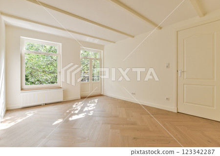 A spacious and airy interior with large windows allowing natural light. The light wood flooring and neutral walls create a serene atmosphere. 123342287