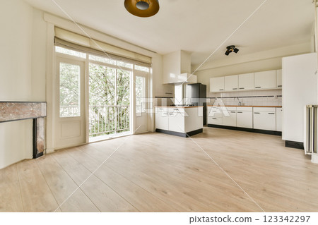 An elegantly designed kitchen featuring white cabinets, wooden flooring, and large windows that invite natural light, creating a bright and airy atmosphere. An elegantly designed kitchen featuring white cabinets, wooden flooring, and large windows that invite natural light, creating a bright and airy atmosphere. 123342297