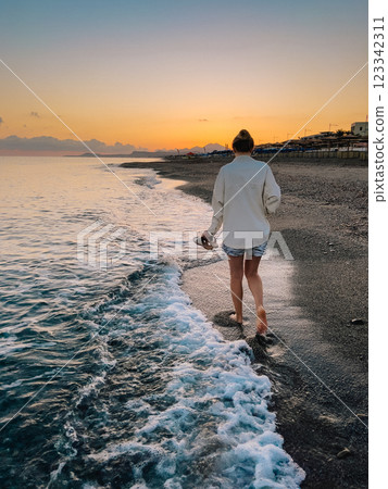 Indulging in Serene Evening Walk Along Shore at Sunset, One with Natures Beauty. tranquil and peaceful moment depicting person walking barefoot along serene beach at sunset time. vertical, film look 123342311