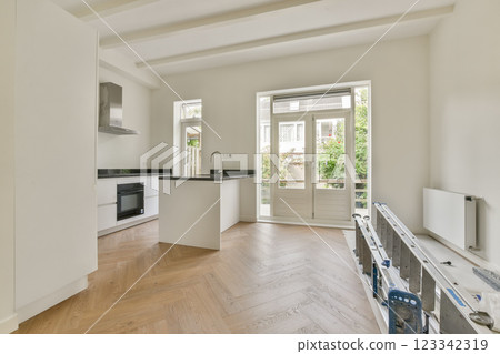 Stylish interior space featuring a kitchen and living area with natural light flooding in, highlighting wooden flooring and contemporary design. 123342319