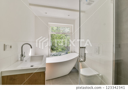 A sleek modern bathroom featuring a freestanding bathtub, minimalist design, and natural light streaming through a window, creating a serene atmosphere. A sleek modern bathroom featuring a freestanding bathtub, minimalist design, and natural light streaming through a window, creating a serene atmosphere. 123342341