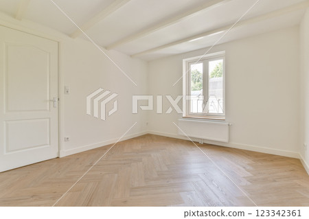 A spacious, empty room featuring white walls, a wooden floor, and a window that allows natural light to illuminate the area, creating a simple and airy atmosphere. A spacious, empty room featuring white walls, a wooden floor, and a window that allows natural light to illuminate the area, creating a simple and airy atmosphere. 123342361