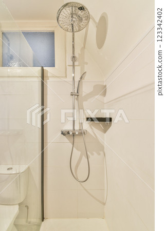 A sleek and contemporary bathroom featuring a stylish showerhead, minimalistic tiles, and a glass partition for an open feel. A sleek and contemporary bathroom featuring a stylish showerhead, minimalistic tiles, and a glass partition for an open feel. 123342402