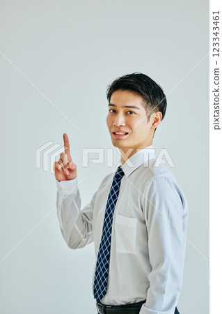 A young man in a dress shirt pointing up 123343461