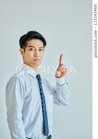一個穿著襯衫的年輕人指著上方 123343469